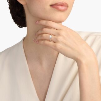 A woman's hand wearing a GIA 2.01 carat round diamond engagement ring, showcasing the beautiful three-stone and lace bridge details in 14K yellow gold.