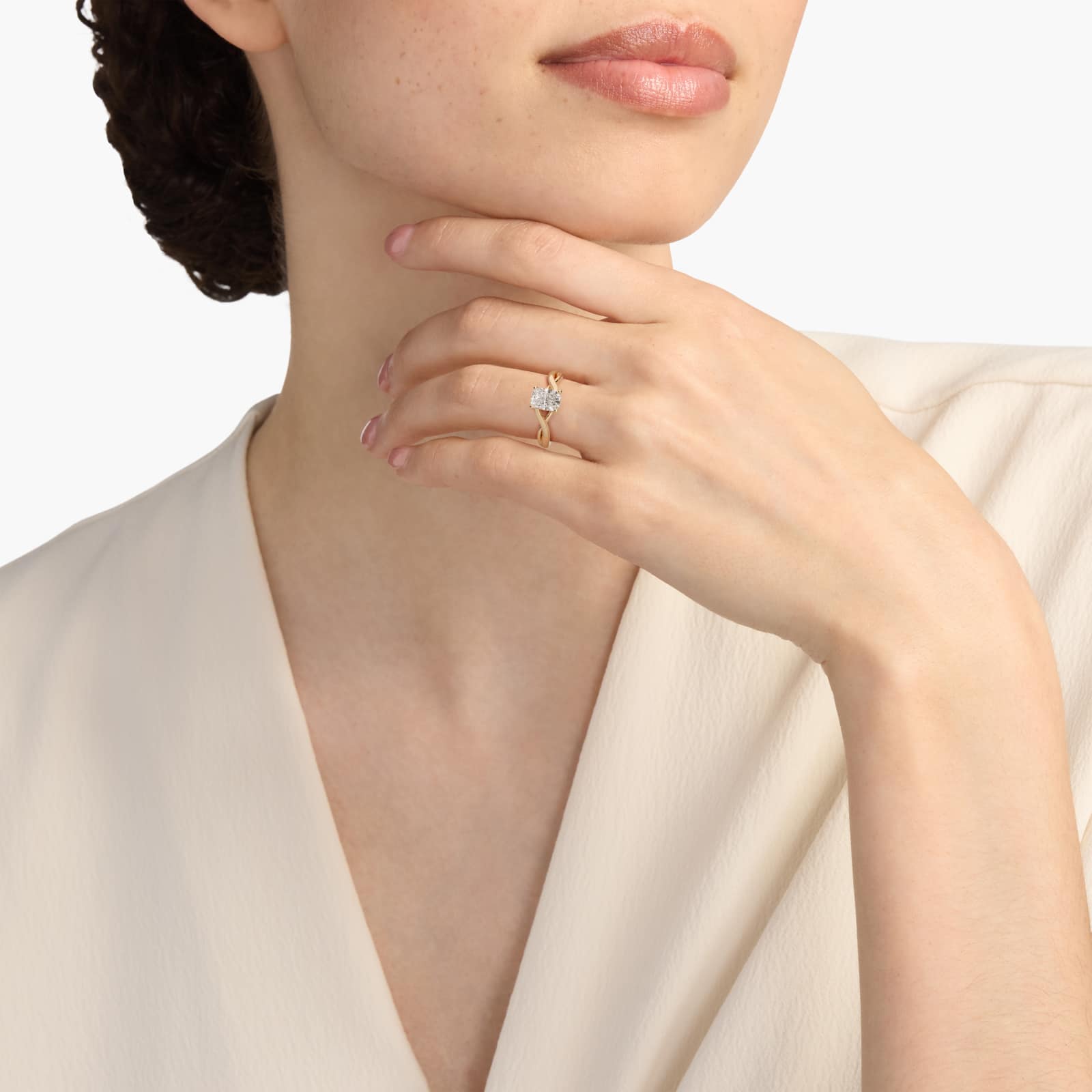 A woman's hand wearing a large 3 carat radiant cut lab grown diamond ring with a D-VVS1 center stone in a yellow gold twist solitaire setting.