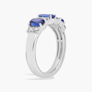 A 14K White Gold 3 Stone Diamond Rings With Sapphires ring (3.60 mm wide) featuring three Oval Blue Sapphires set in prongs, accented by 0.31 CTW Round Diamonds on the shank.