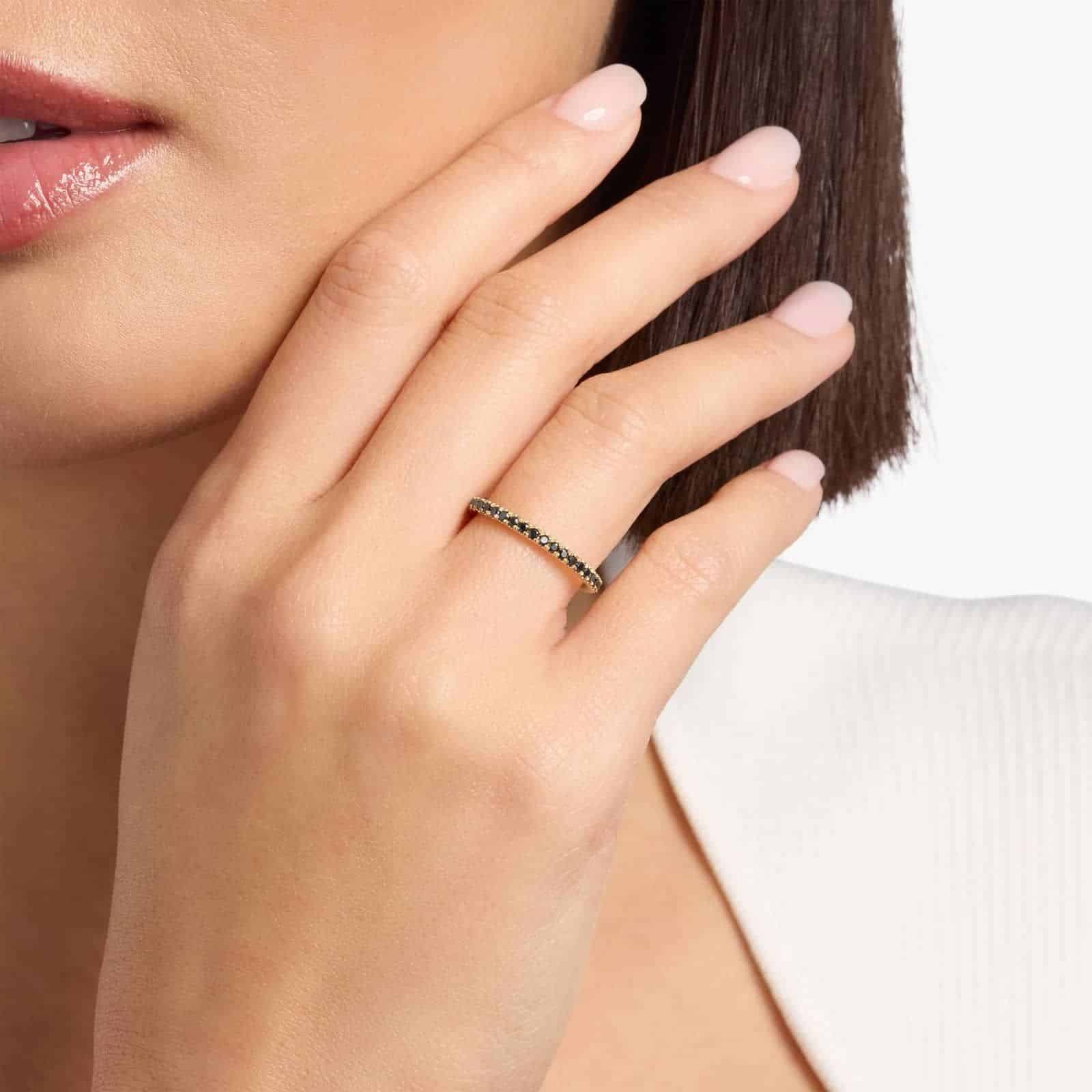 A Riviera Noir Pavé Black Diamond Black Wedding Rings For Women band (1.50mm) in 18K Yellow Gold with 0.50 CTW black diamonds in women hands view.