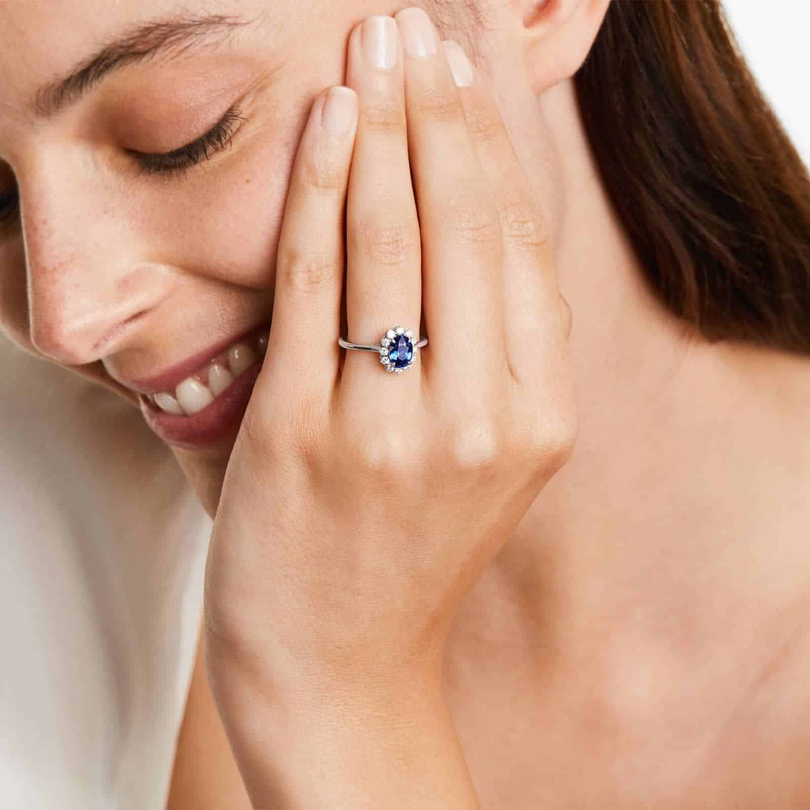 oval-halo-engagement-rings-with-diamonds-and-sapphires-18k-white-gold model view 2 An 18K White Gold Oval Halo Engagement Rings With Diamonds and Sapphires ring featuring a 1.05 Carat Oval Blue Sapphire center stone and a 0.27 Carat Total Weight round diamond halo.