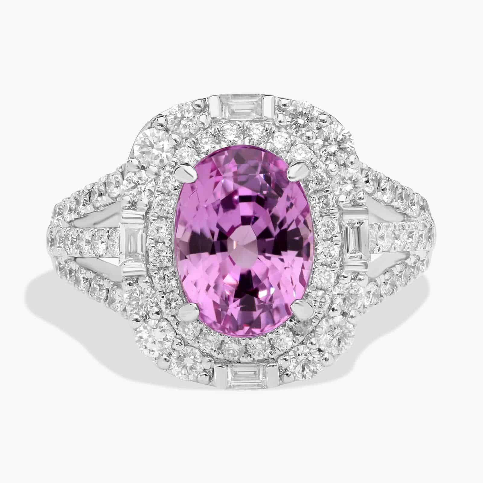 An 18K White Gold Pink Sapphire and Diamond Ring, designed as a Cocktail Ring, featuring a 5.04 Carat Oval Pink Sapphire center stone surrounded by a halo of Round and Baguette diamonds (0.94 CTW total).
