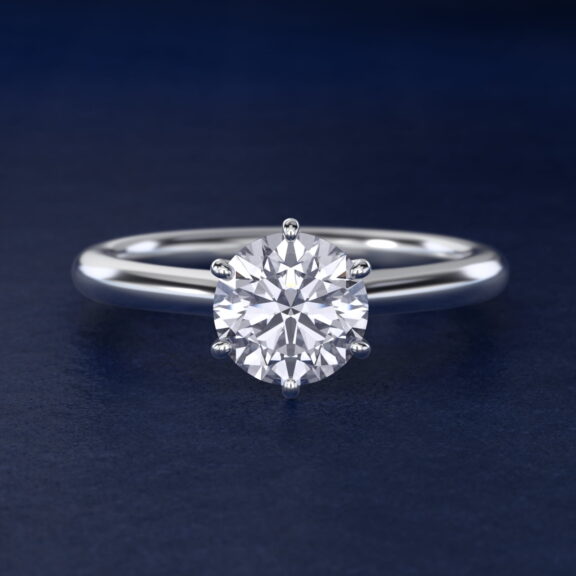 Platinum six prong solitaire engagement rings under $2,500 featuring a 1.5 carat round colorless lab grown diamond on a petite 1.80mm Nouveau band.